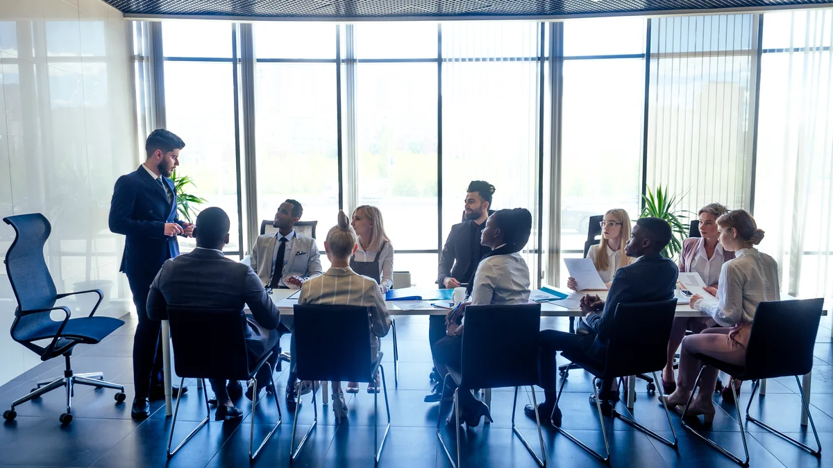 Colleagues meet in a glass-walled boardroom — Advisory