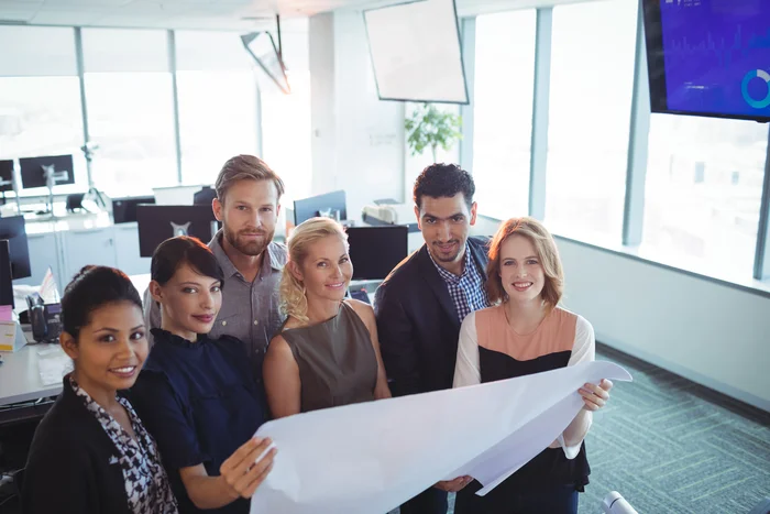 A diverse team poses together in a bright meeting room.