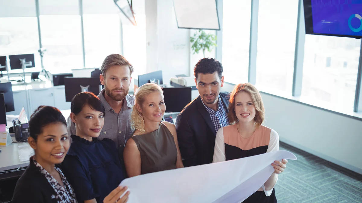 Several professionals lean over documents in a planning session.