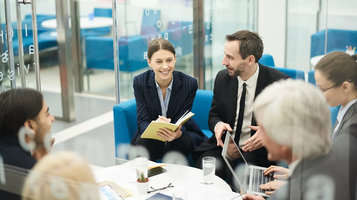 A group talks in a bright workplace corridor.