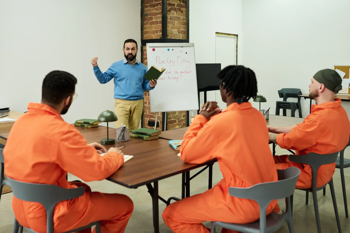 A facilitator leads a session with a group in custody uniforms.