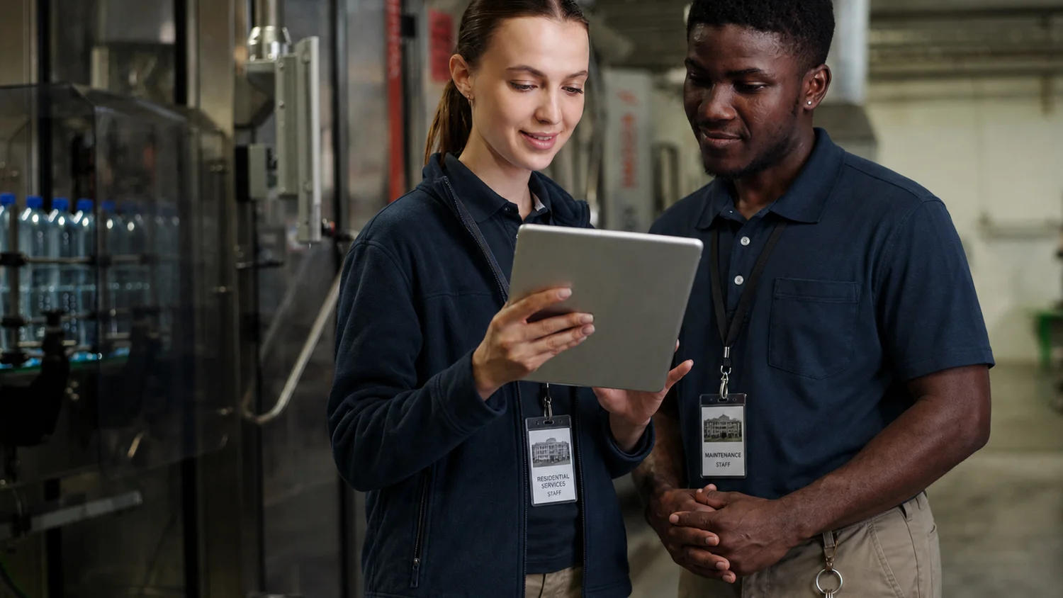 Two colleagues review a workflow together on a tablet in an industrial facility