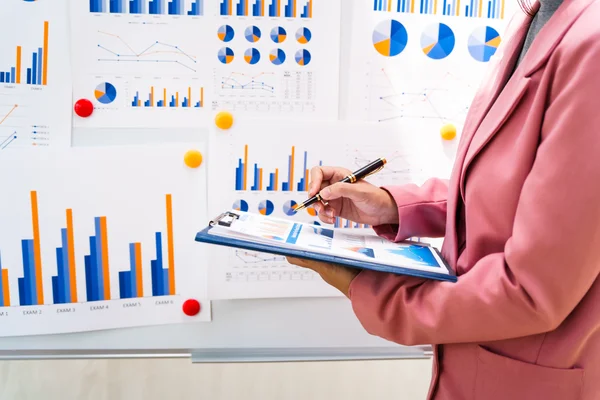 A manager presents data beside a wall of charts.