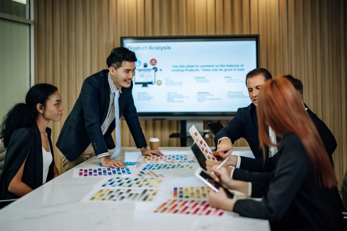 A team works around a table with a digital presentation screen
