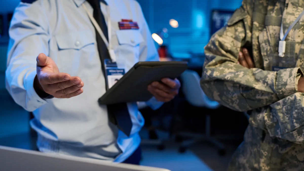 A professional holds a clipboard while staff stand behind them.